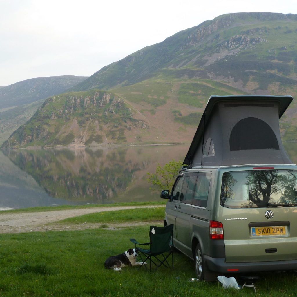 campervan next to a loch with a dog