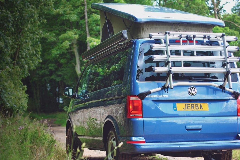 Blue Campervan with a Pop Top Roof near the forest