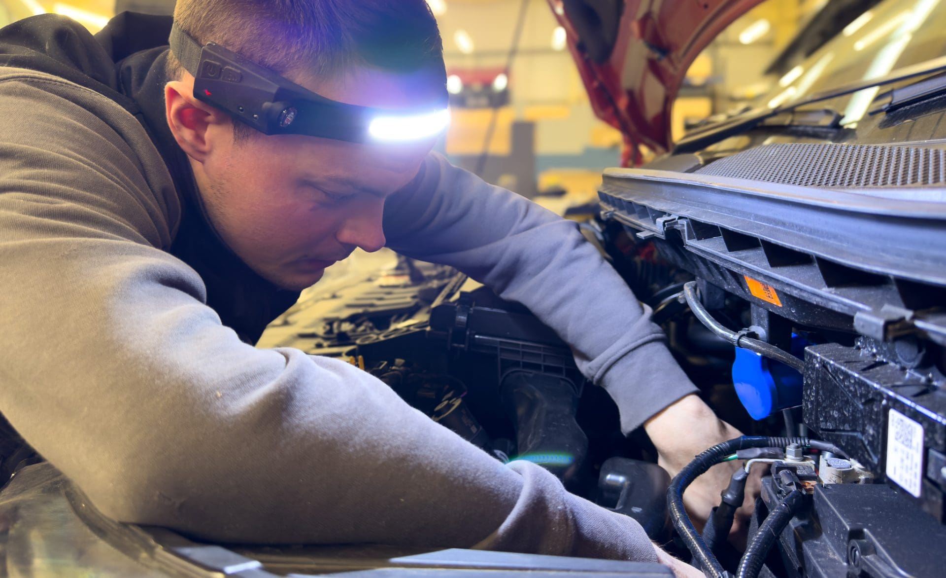 A service technician looking into the engine bay of a campervan.