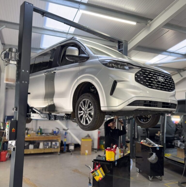 A Ford Transit Custom Van in the air suspended by a garage lift funded by UK Grant.