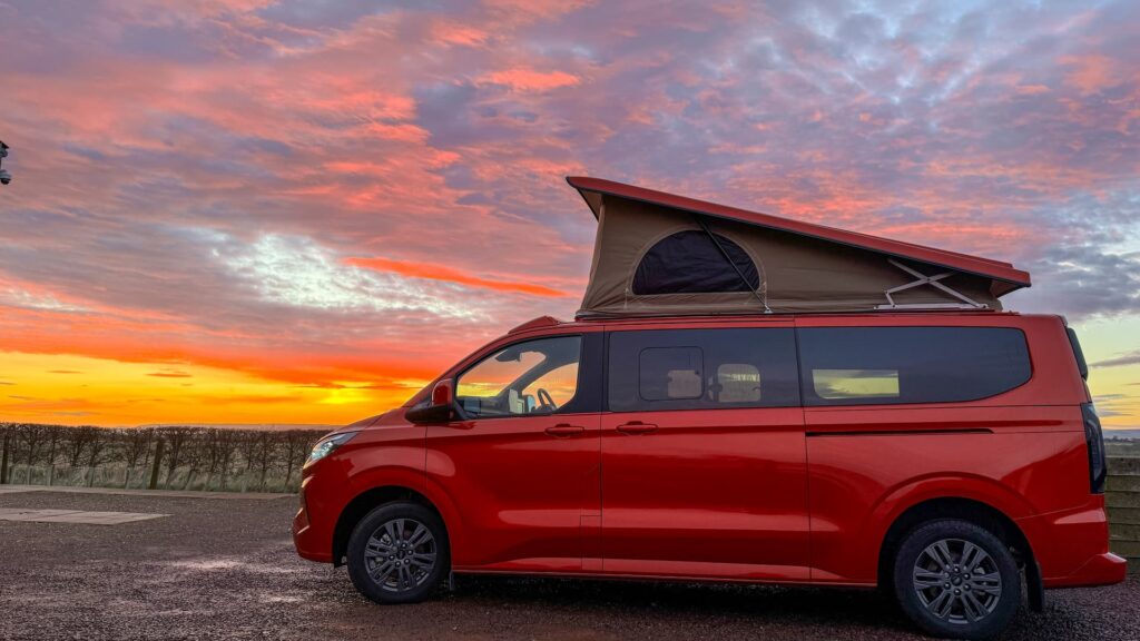 Side View of a Red Ford Transit Custom Campervan with Elevating Roof, 2026.